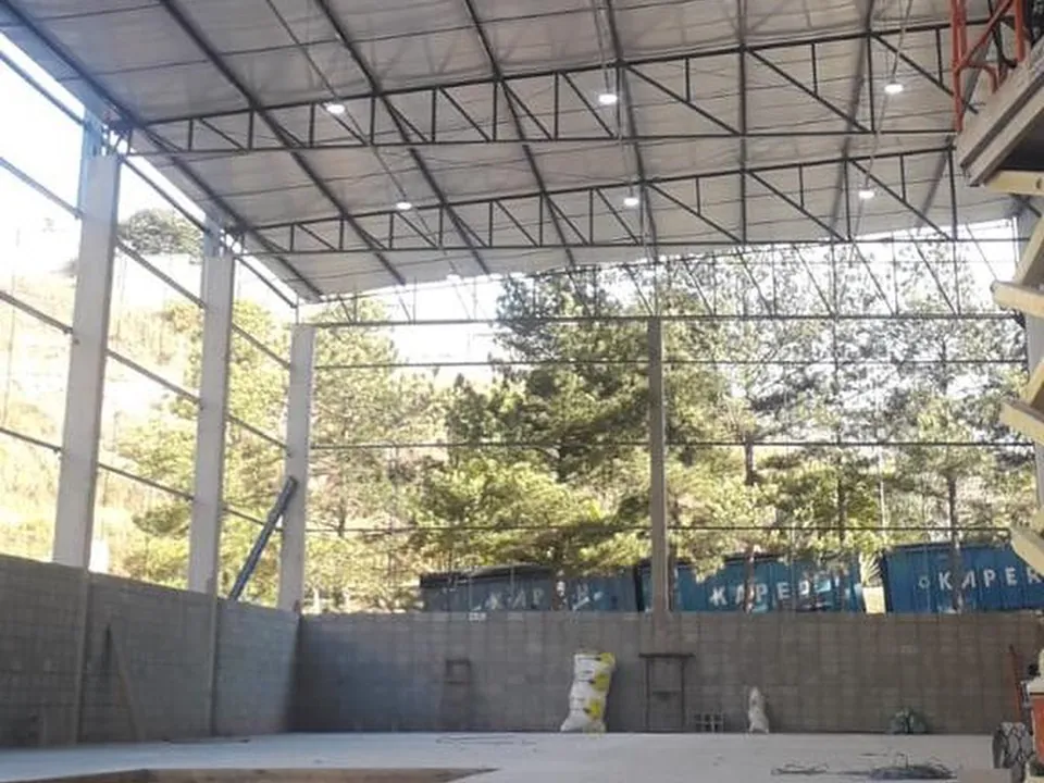 Interior do galpão da Gráfica Plural com estrutura metálica da cobertura