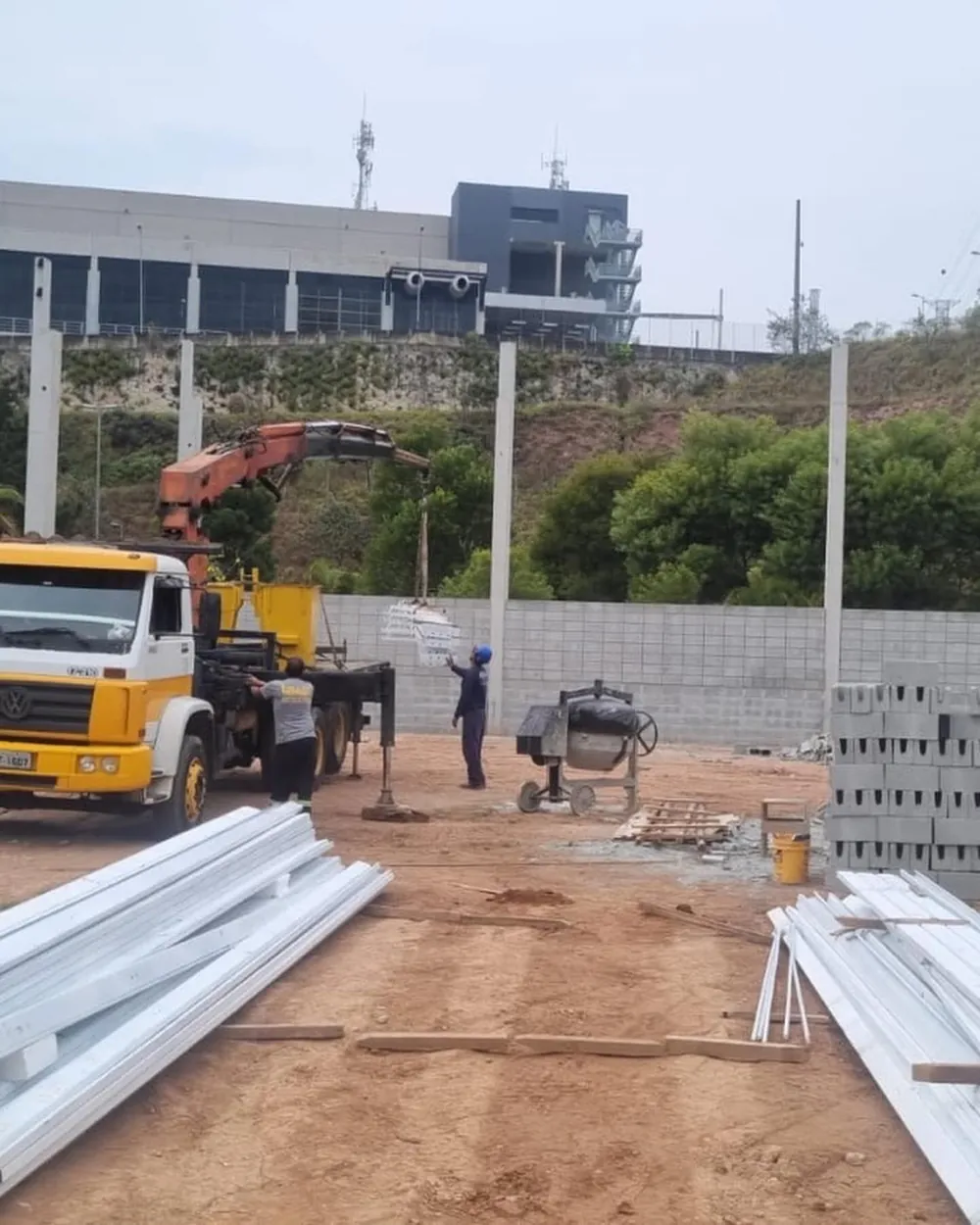 Caminhão com guindaste montando a estrutura de um galpão